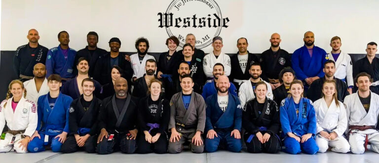 group of students and instructors posing for a team picture lined up in rows along the wall