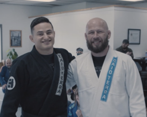 man in black gi with caio terra patch smiling standing next to man in white gi with a caio terra patch smiling