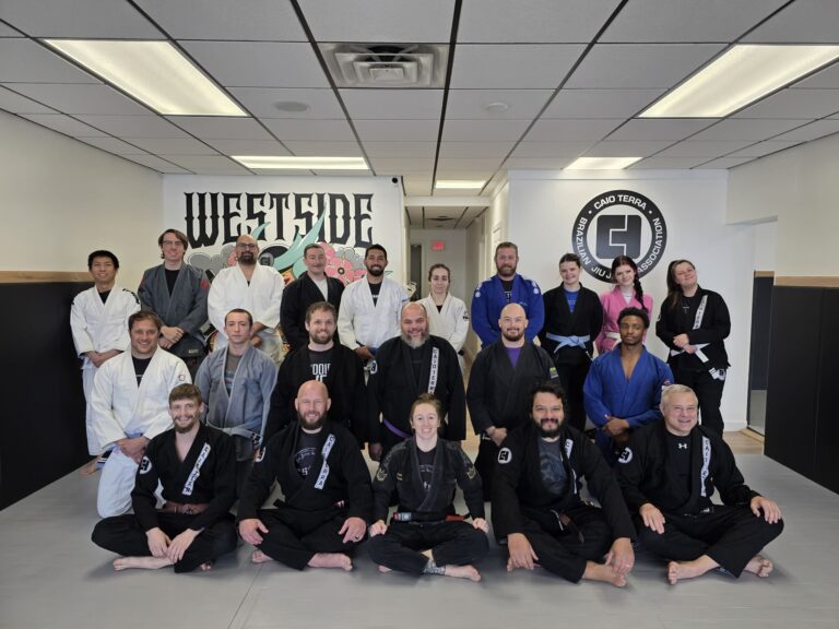 students wearing gi's lined up for a photo front row seated, second row kneeling, third row standing